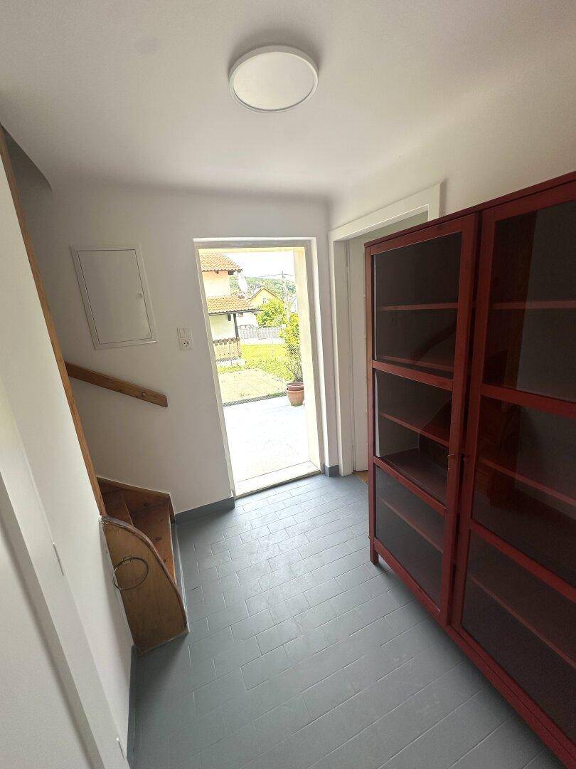 Eingangsbereich mit rotem Schrank und Haustür, die ins Freie führt.
