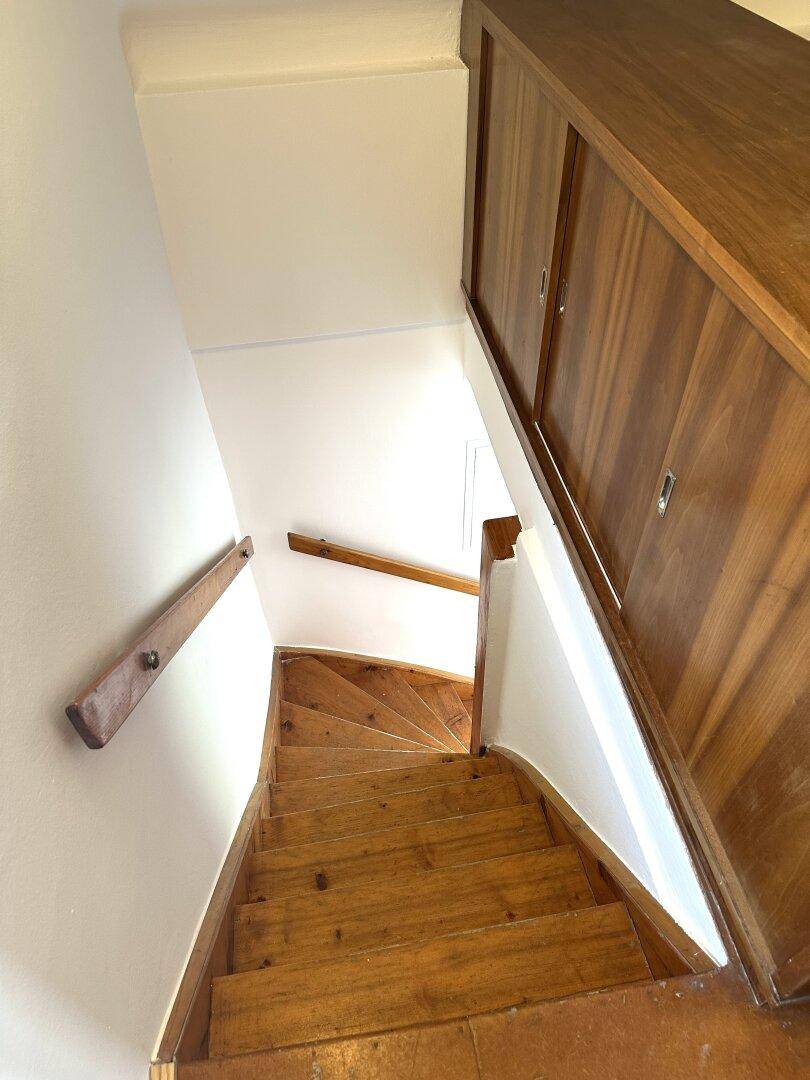 Holztreppe mit Holzgeländer und integrierten Holzschränken entlang der Wand.