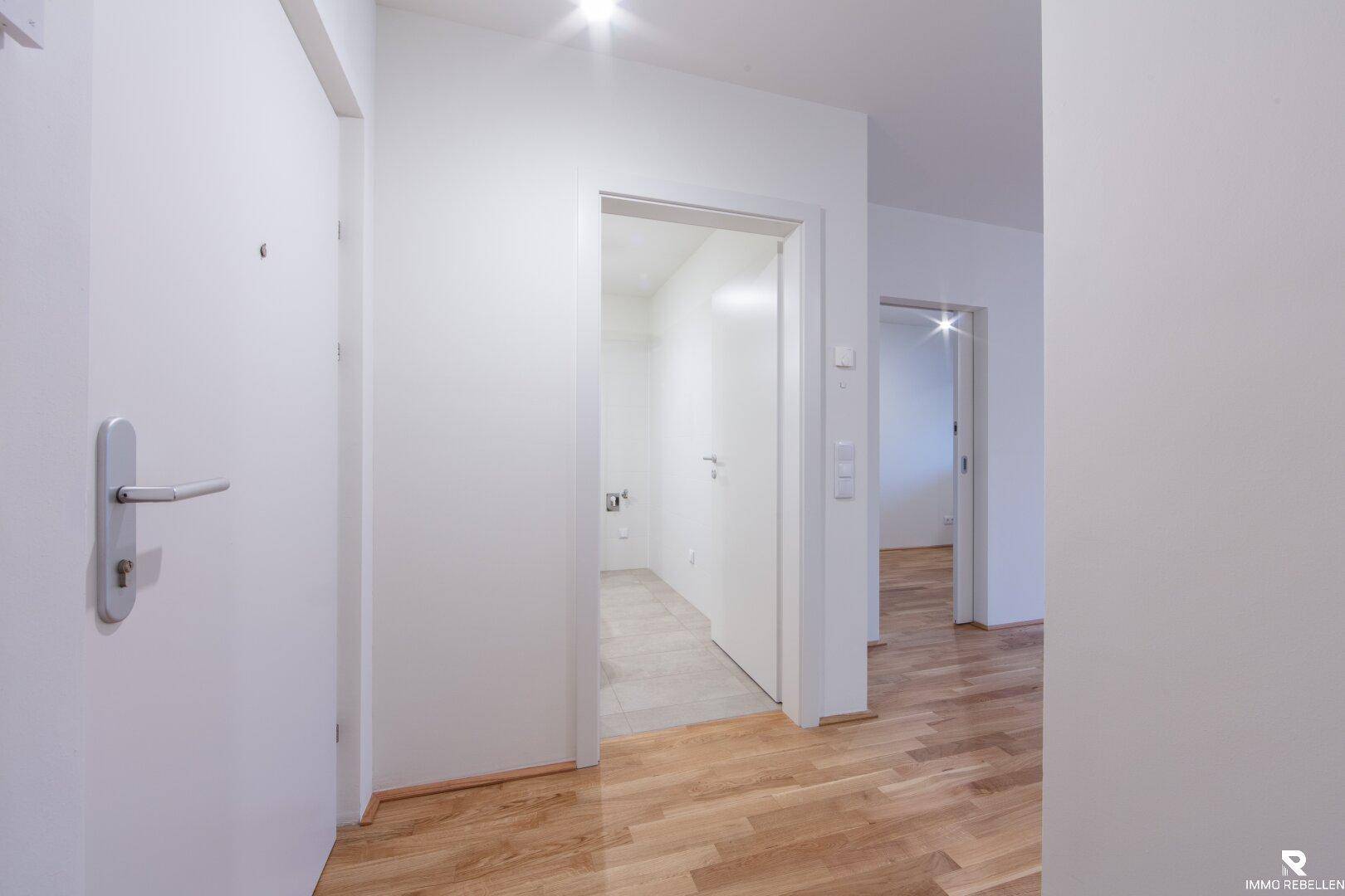 Heller Flur mit weißen Türen, der zu verschiedenen Räumen der Wohnung führt.