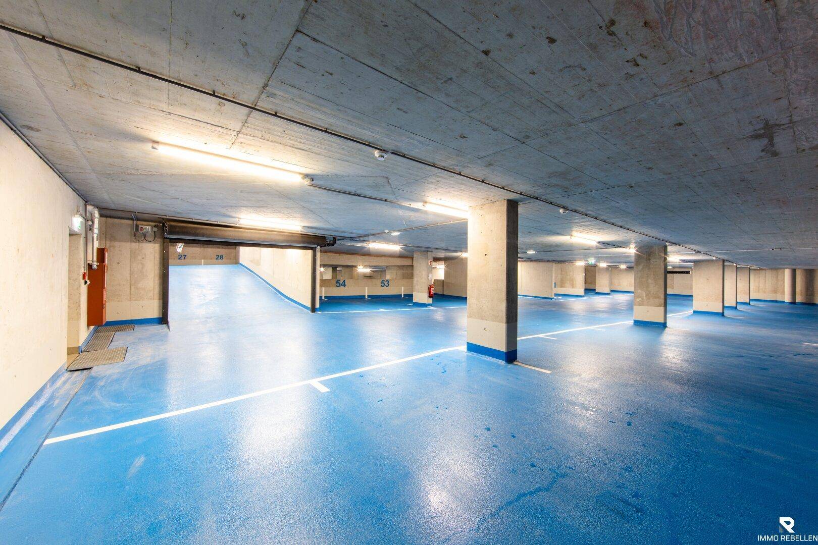 Geräumige Tiefgarage mit blauer Bodenmarkierung und Betonpfeilern.