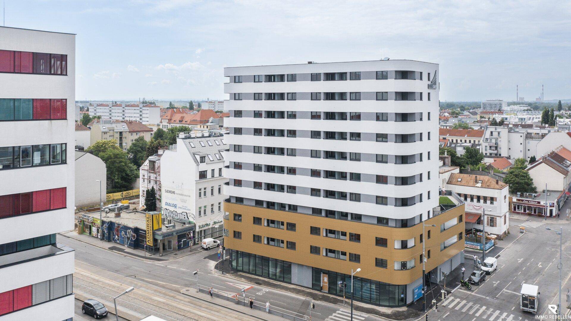 Modernes Wohngebäude mit markanter Fassade in städtischer Umgebung, von oben fotografiert.