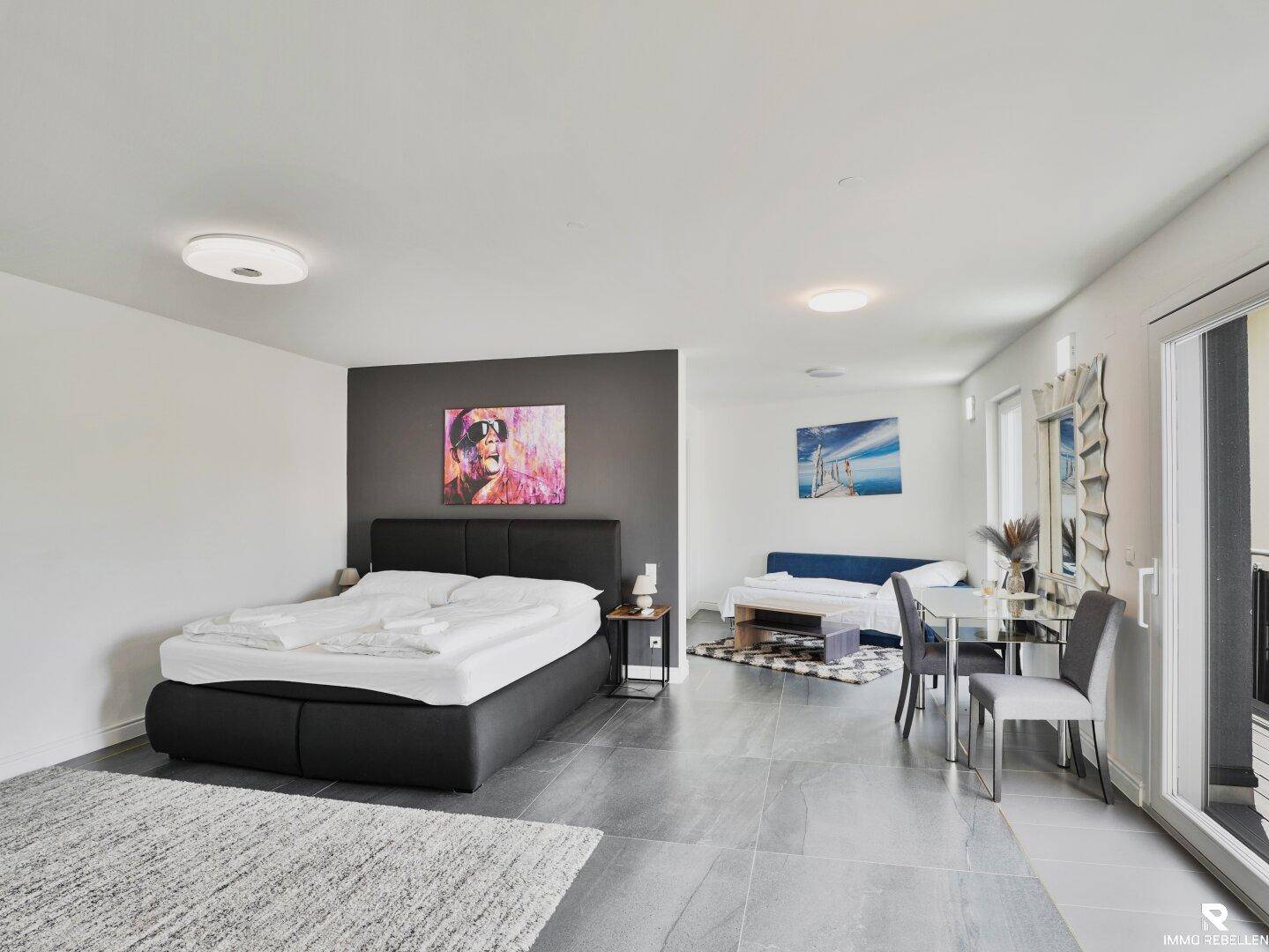 Geräumiges Schlafzimmer mit Doppelbett, Sitzbereich und Zugang zu einem Balkon.