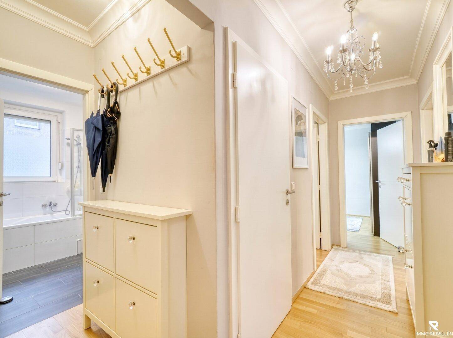 Heller Flur mit Garderobe, Schuhschrank und Zugang zu einem Badezimmer.