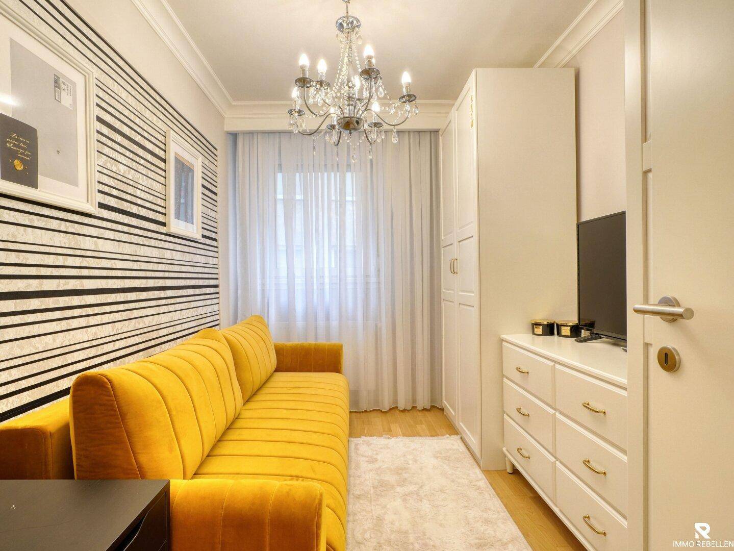 Farbenfrohes Zimmer mit gelbem Sofa, Schrank und gestreifter Akzentwand.