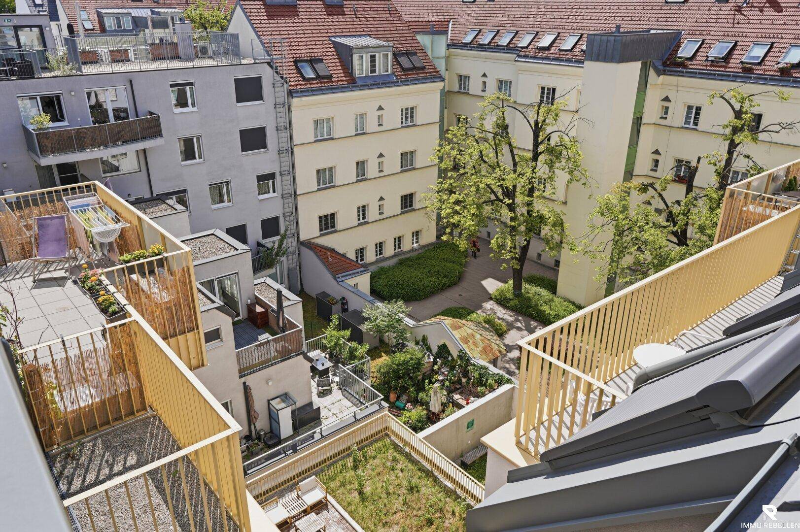 Luftaufnahme eines Wohnkomplexes mit begrünten Innenhöfen und Dachterrassen.