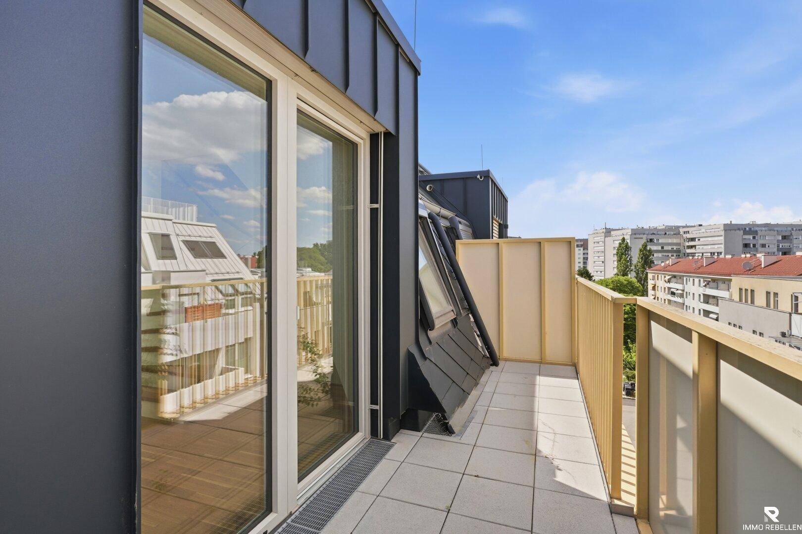 Heller Balkon mit Fliesenboden und weitem Blick über die umliegende Stadtlandschaft.
