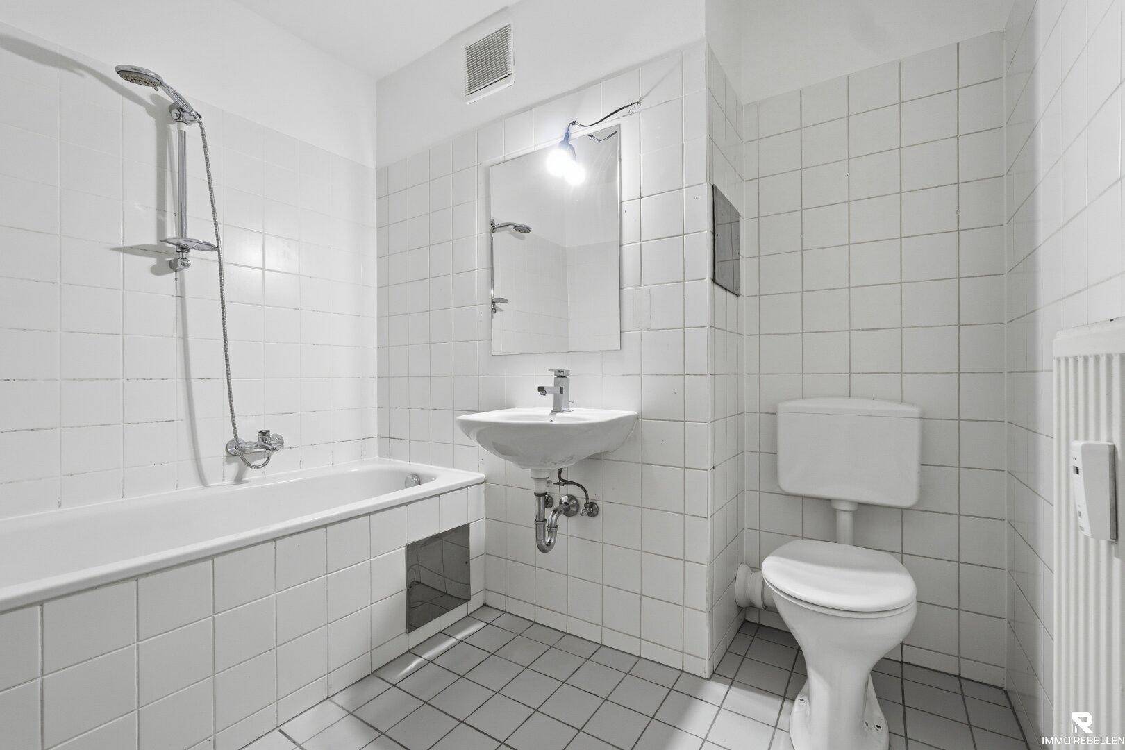 Funktionales Badezimmer mit Badewanne, Duschfunktion, WC und Waschbecken.