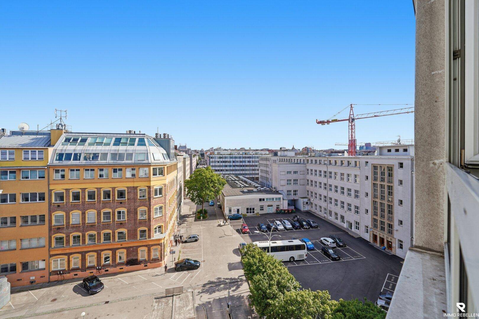 Weitläufiger Blick über die Stadt mit umliegenden Gebäuden und einem Kran am Horizont.