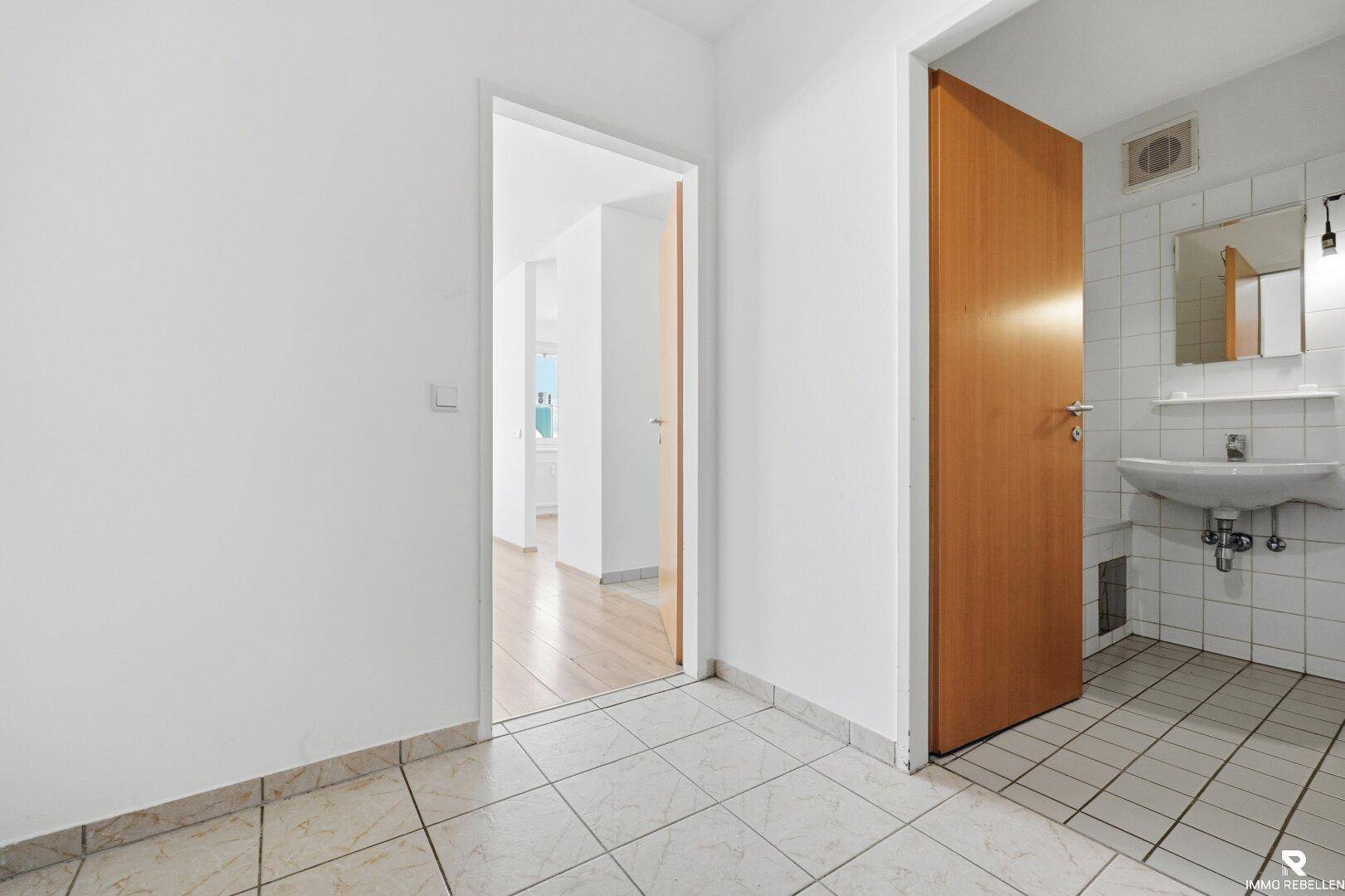 Flur mit Fliesenboden, der zu einem Badezimmer und weiteren Zimmern führt.