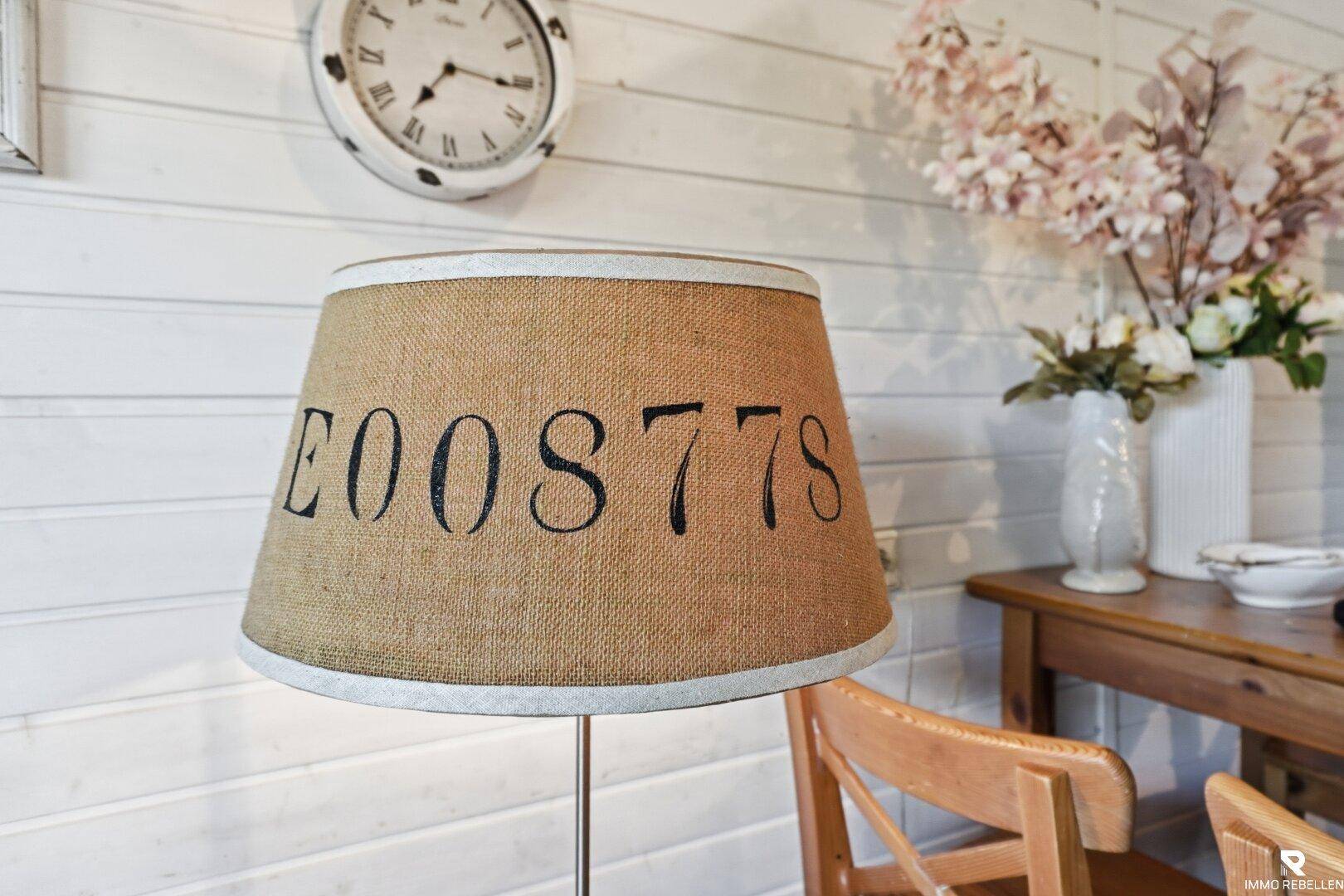 Nahaufnahme eines dekorativen Lampenschirms und Blumenarrangements auf einem Holztisch.