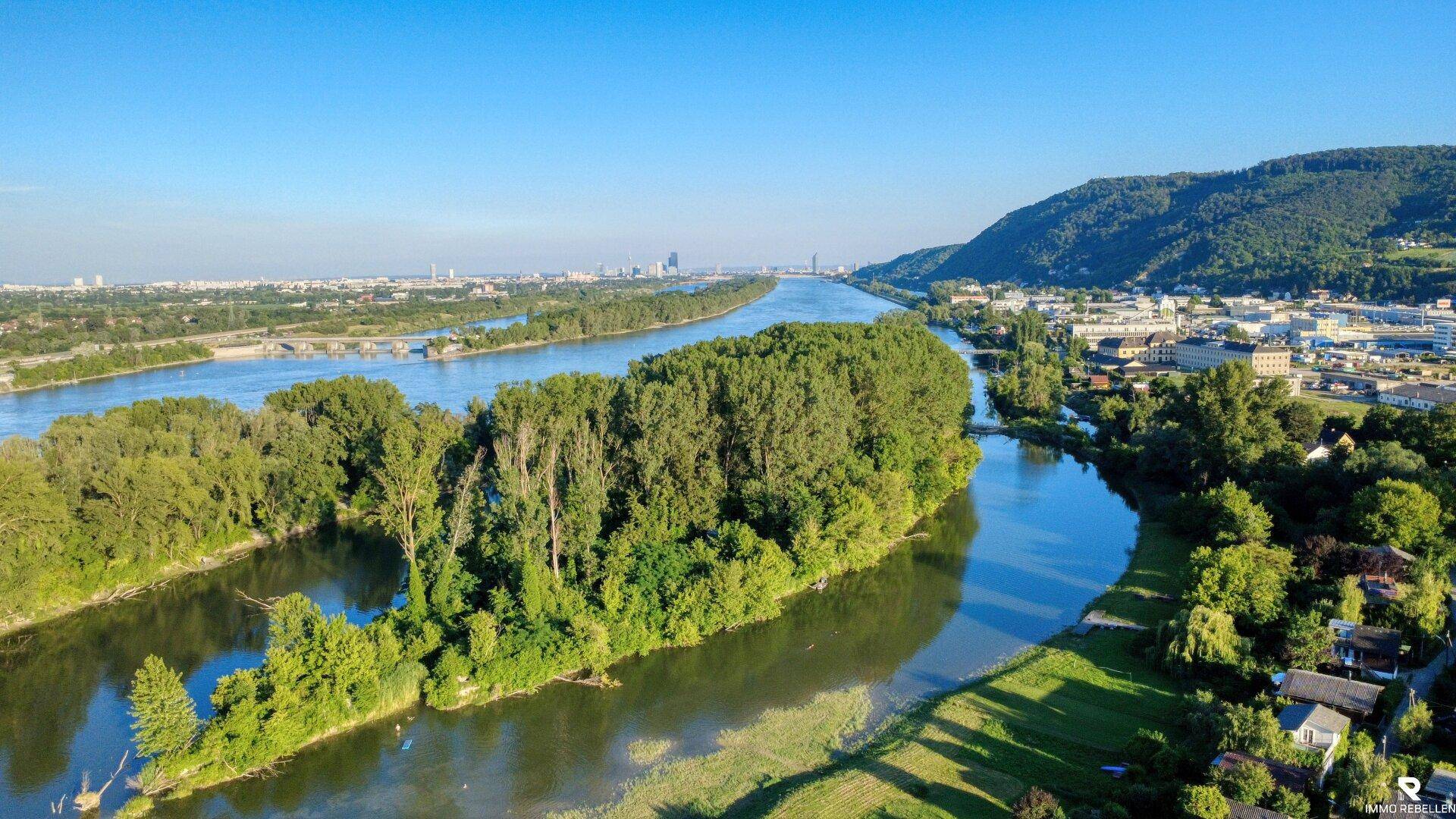 Weitläufige Luftaufnahme einer Flusslandschaft mit Inseln und einer Stadt am Horizont.