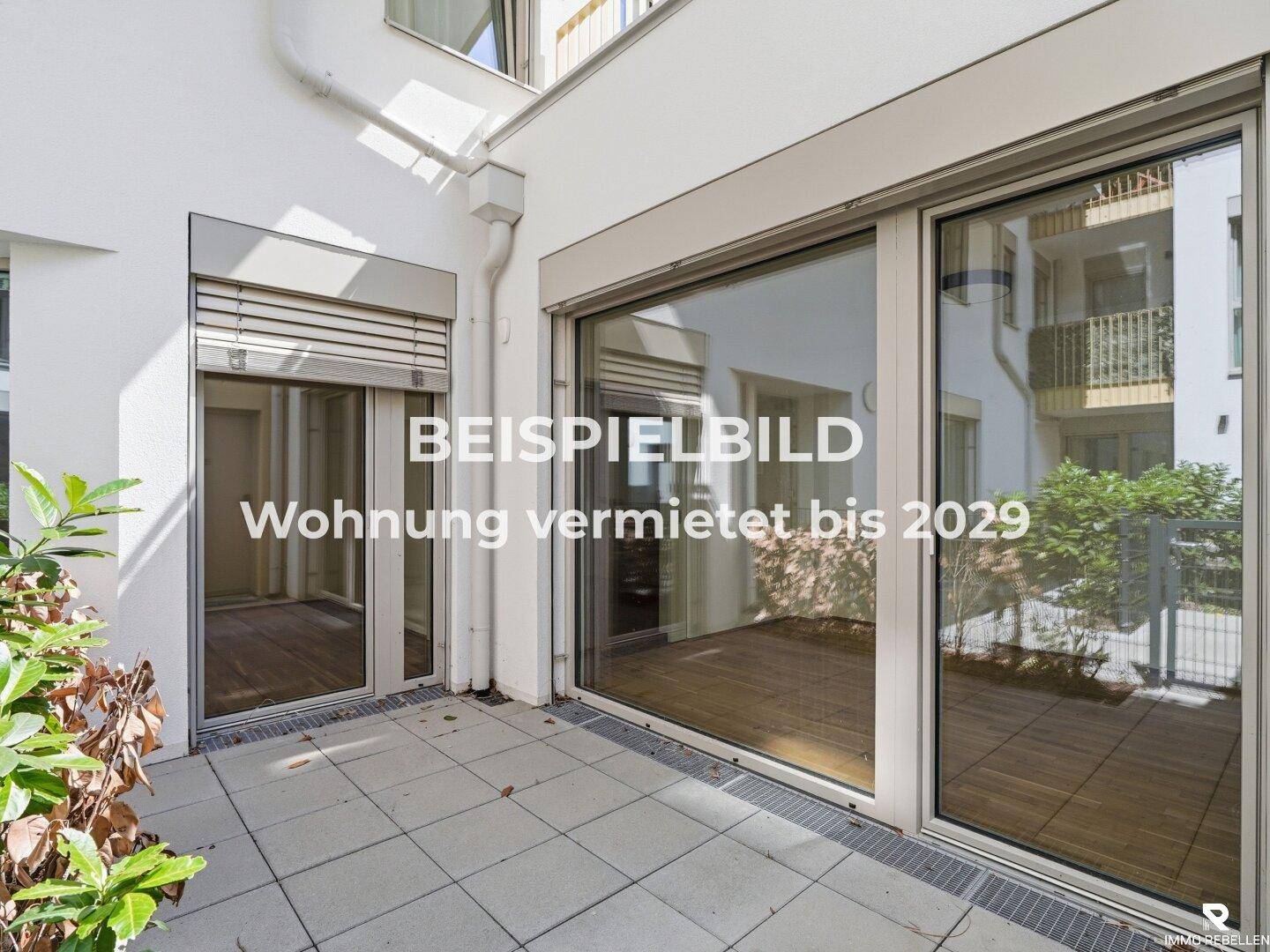 Geräumige Außenterrasse mit Fliesenboden und großen Glasfronten zum Wohnbereich.