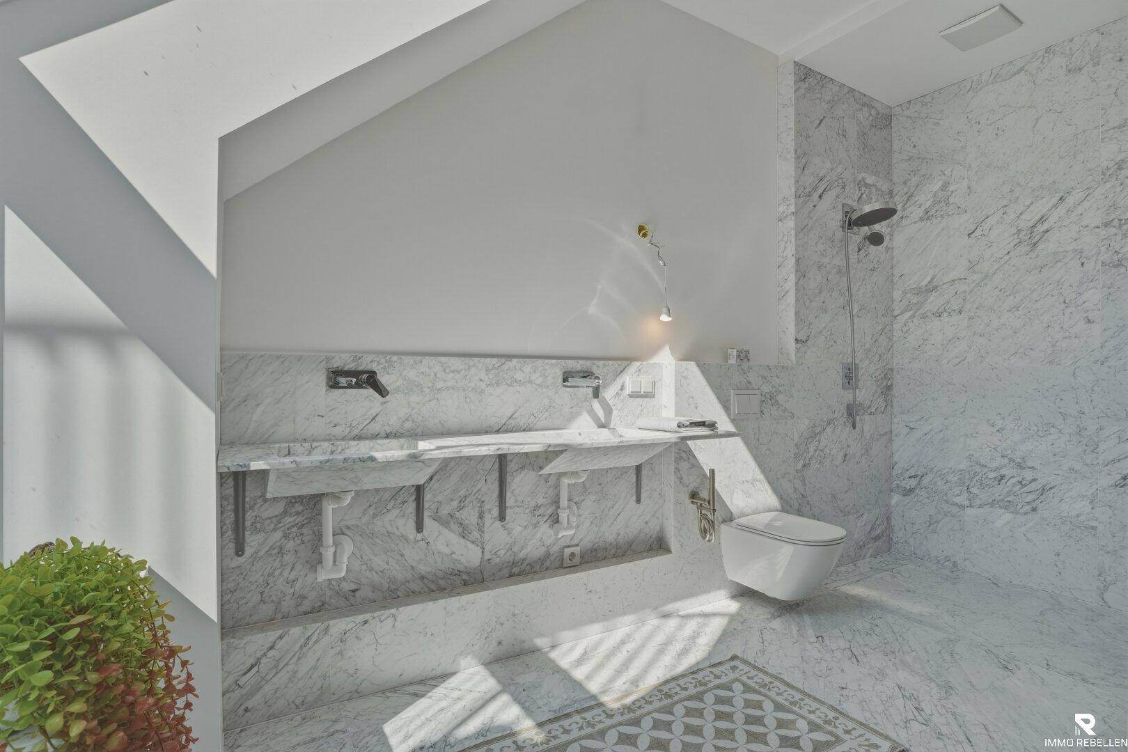 Elegantes Badezimmer mit Marmorfliesen, Doppelwaschbecken und moderner Duscharmatur.
