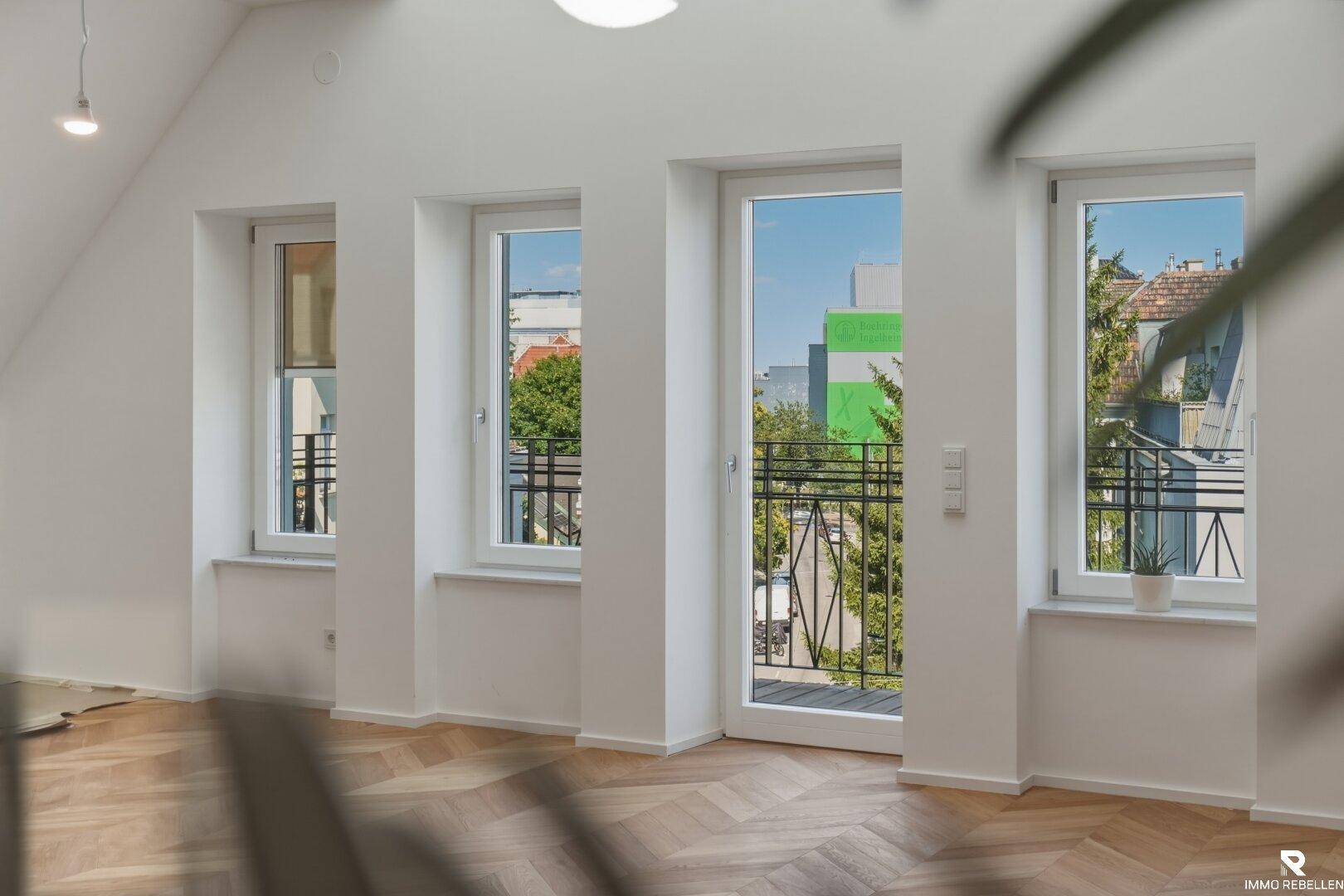 Große Fensterfront mit Blick ins Grüne und auf die umliegenden Gebäude.