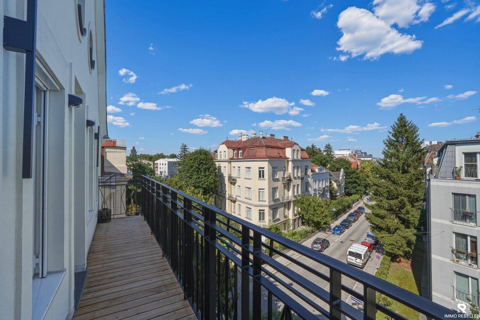 Langer Balkon mit Holzboden und Blick auf die Straße und historische Gebäude.
