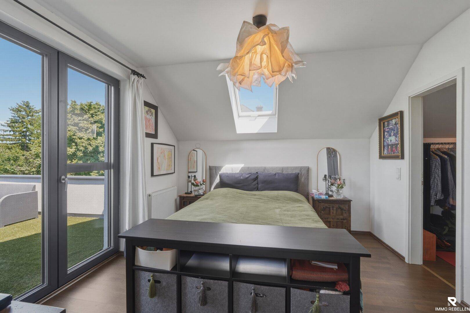 Schlafzimmer im Dachgeschoss mit Zugang zur begrünten Dachterrasse und Dachfenster.