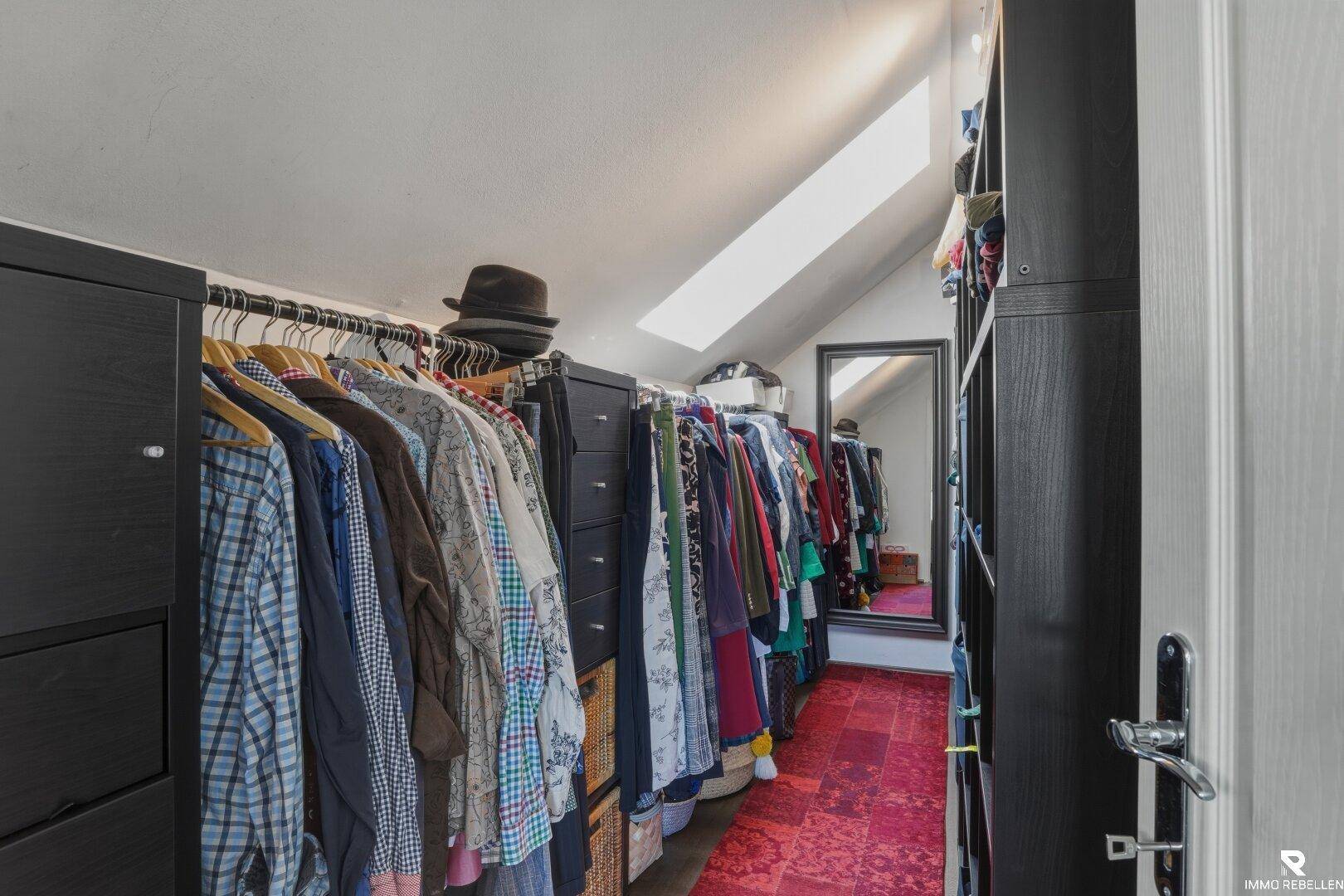Geräumiger begehbarer Kleiderschrank mit viel Stauraum und Dachfenster.