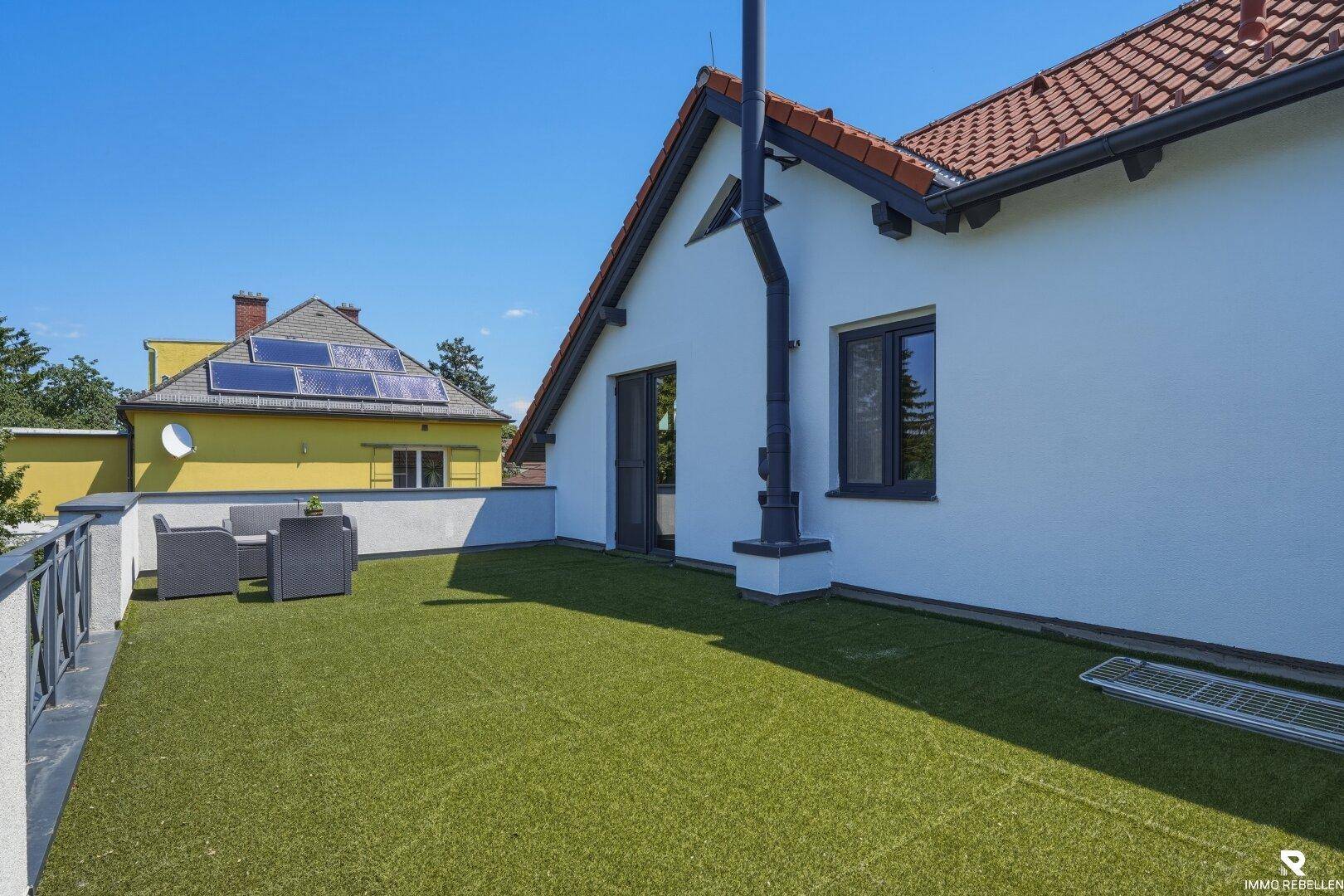 Begrünte Dachterrasse mit Sitzgelegenheiten und Blick auf die Umgebung.