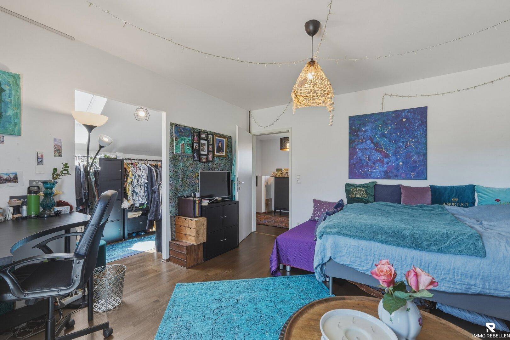 Schlafzimmer mit Schreibtisch und offenem Zugang zu einem begehbaren Kleiderschrank.