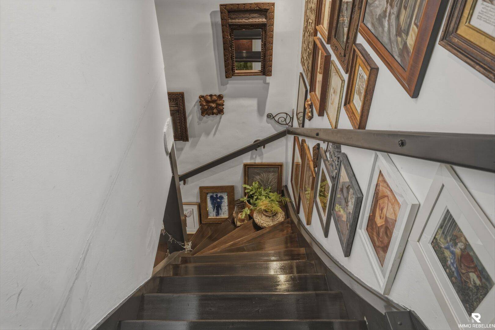 Dunkle Holztreppe mit vielen gerahmten Bildern an der Wand, die einen kunstvollen Aufgang schafft.