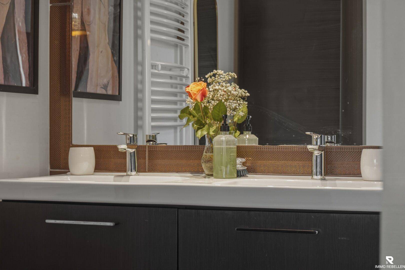 Modernes Badezimmer mit Doppelwaschbecken, großem Spiegel und Handtuchheizkörper im Hintergrund.