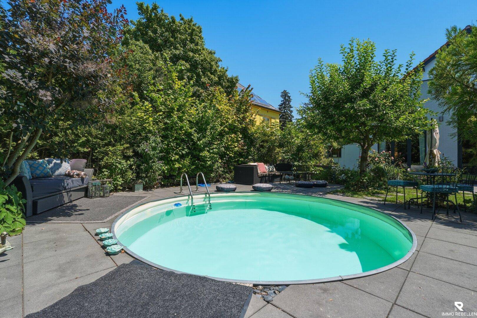 Großer Garten mit einem runden Pool und einer gepflasterten Terrasse, ideal für Entspannung im Freien.