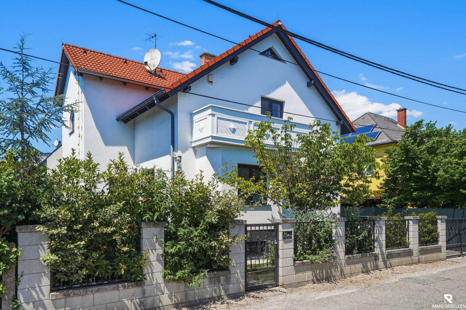 Ansicht des Hauses von außen mit einem Balkon und einem markanten roten Ziegeldach.