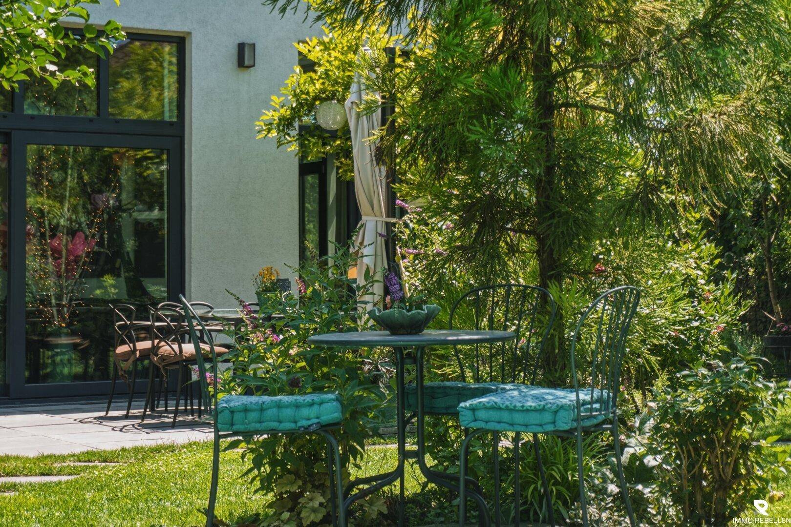 Idyllischer Gartenbereich mit gemütlicher Sitzgruppe und üppiger Bepflanzung, ideal zum Entspannen.