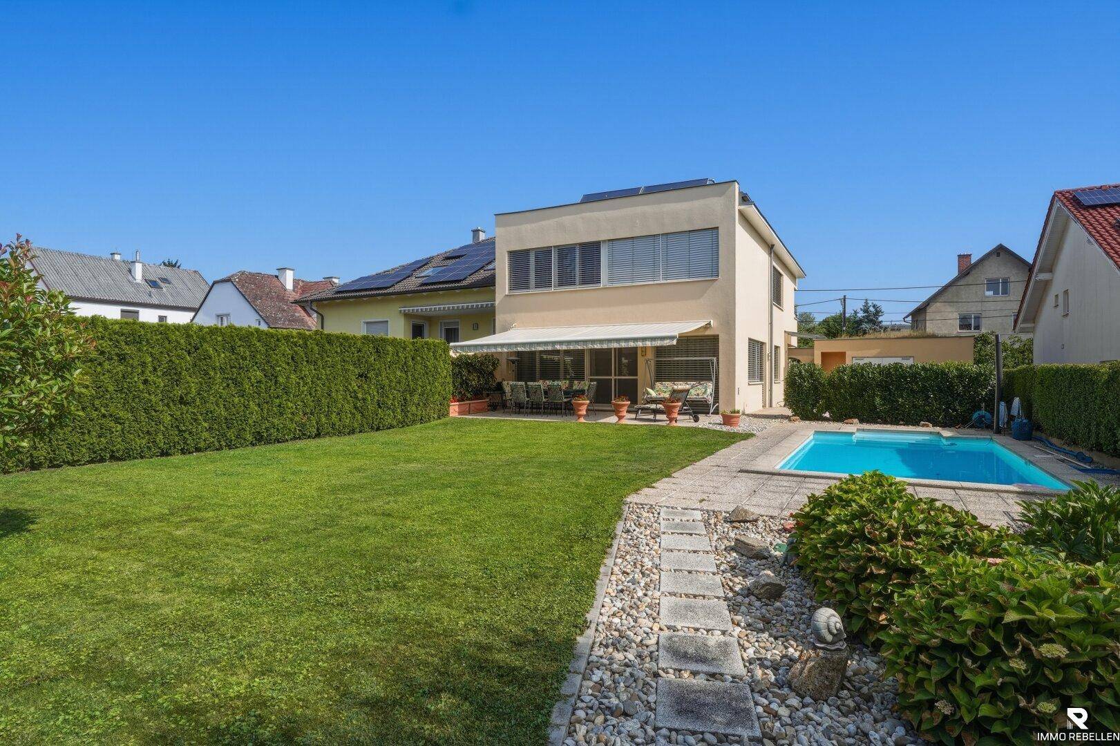 Großer, gepflegter Garten mit Rasenfläche, Swimmingpool und einer Terrasse am Haus.