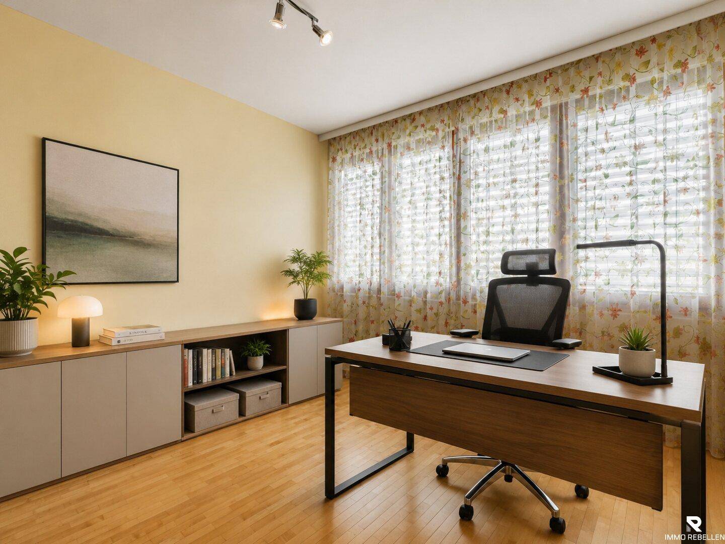 Helles Arbeitszimmer mit Holzboden, großem Schreibtisch und Fensterfront mit floralen Vorhängen.