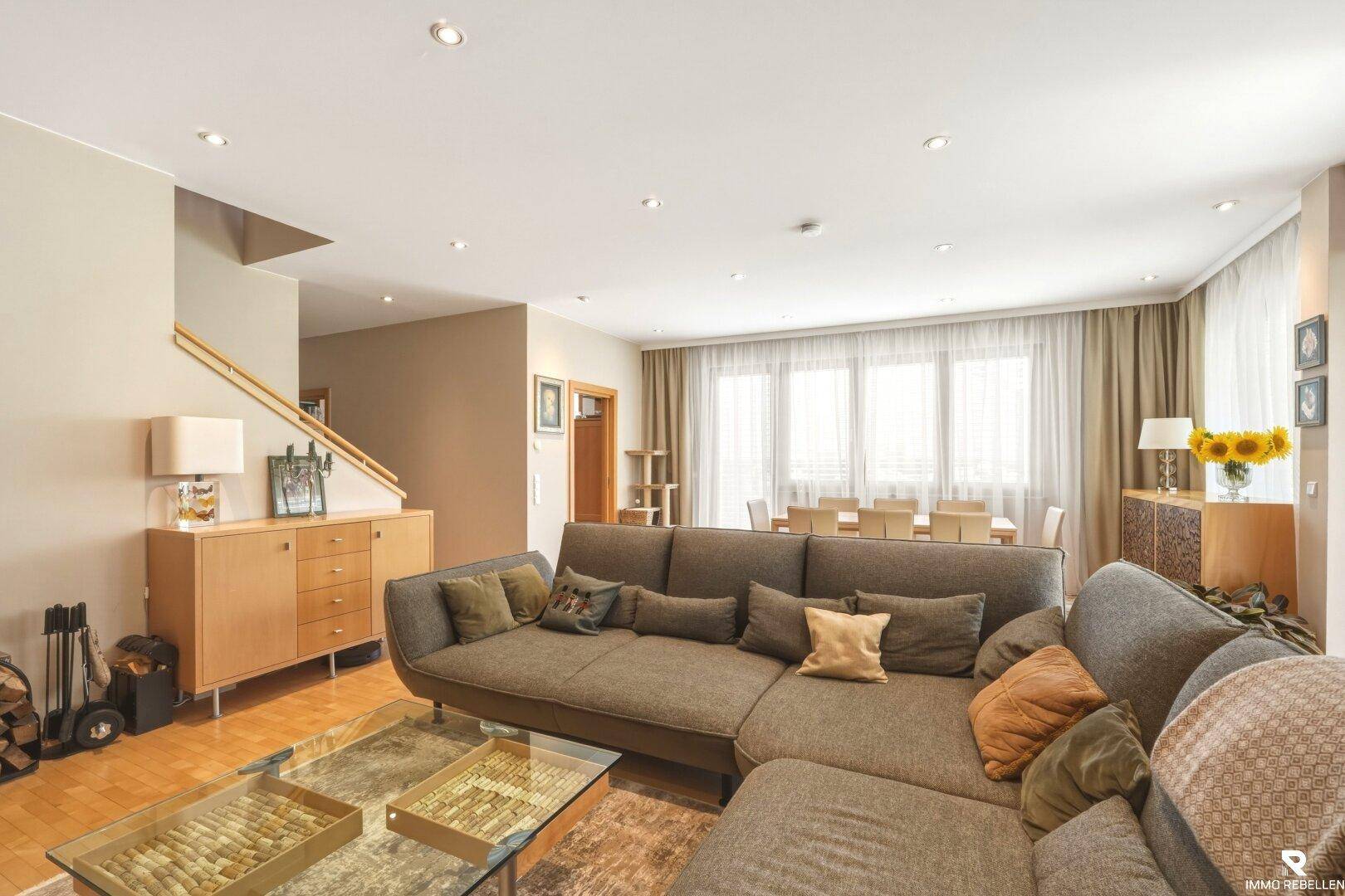 Gemütlicher Wohnbereich mit großem Ecksofa, Couchtisch und Blick auf den Essbereich im Hintergrund.
