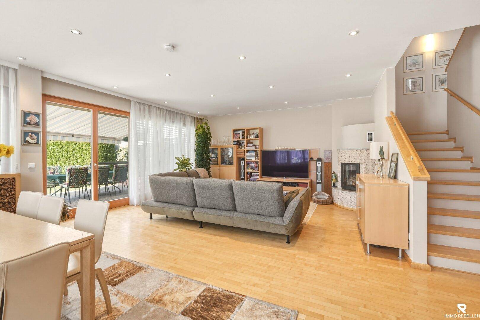 Heller Wohn- und Essbereich mit Holzboden, Kamin und Zugang zur Terrasse im Außenbereich.