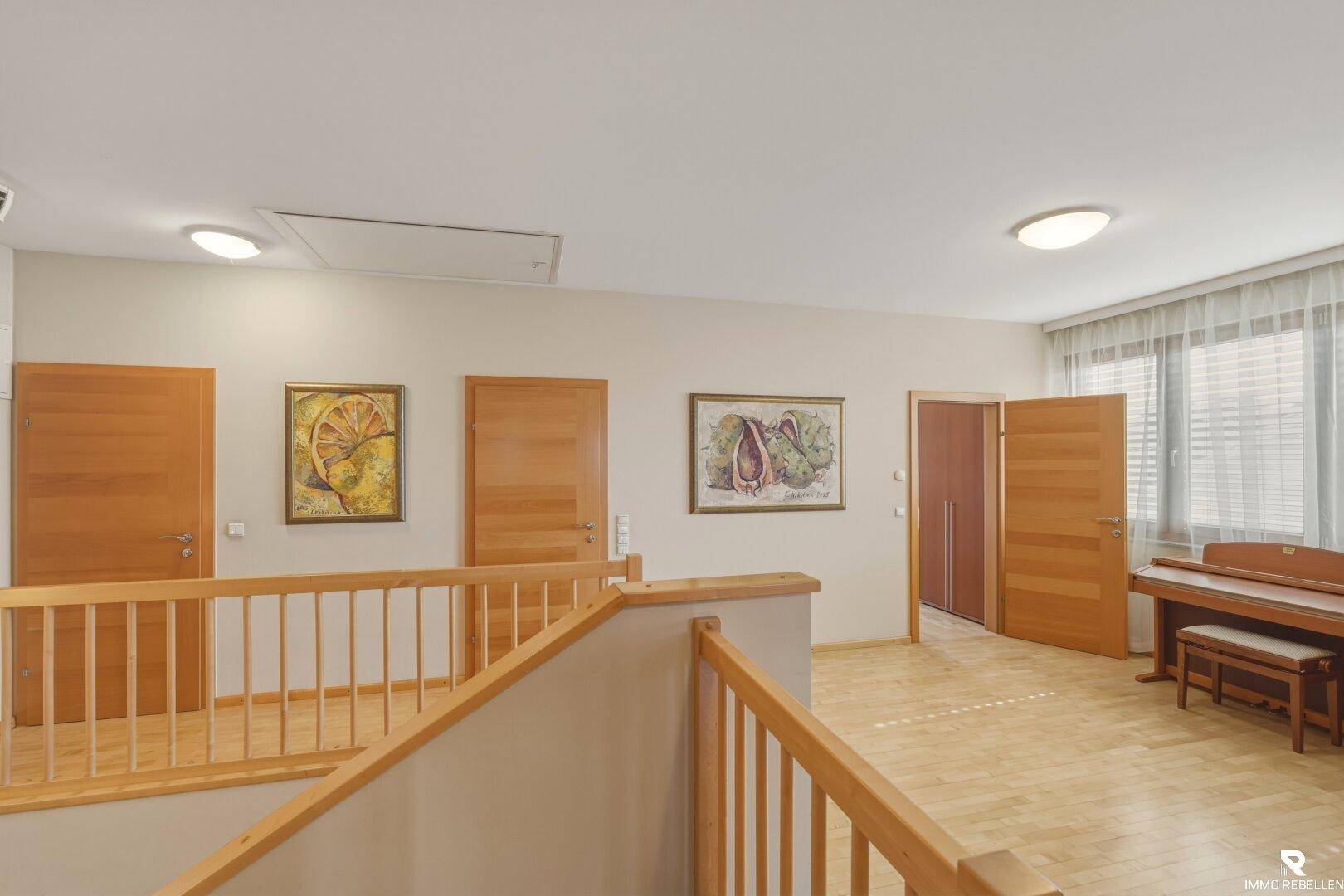 Heller Flur im Obergeschoss mit Holzboden, Treppengeländer und Blick auf weitere Räume.