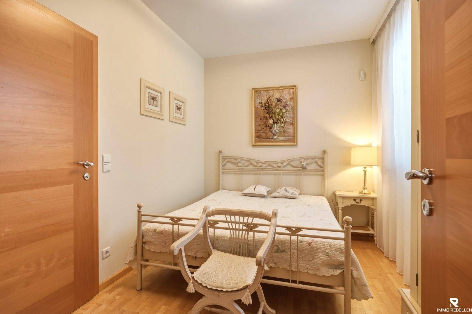 Helles Schlafzimmer mit Holzboden, klassischem Bettgestell und Nachttischlampe für gemütliche Abende.