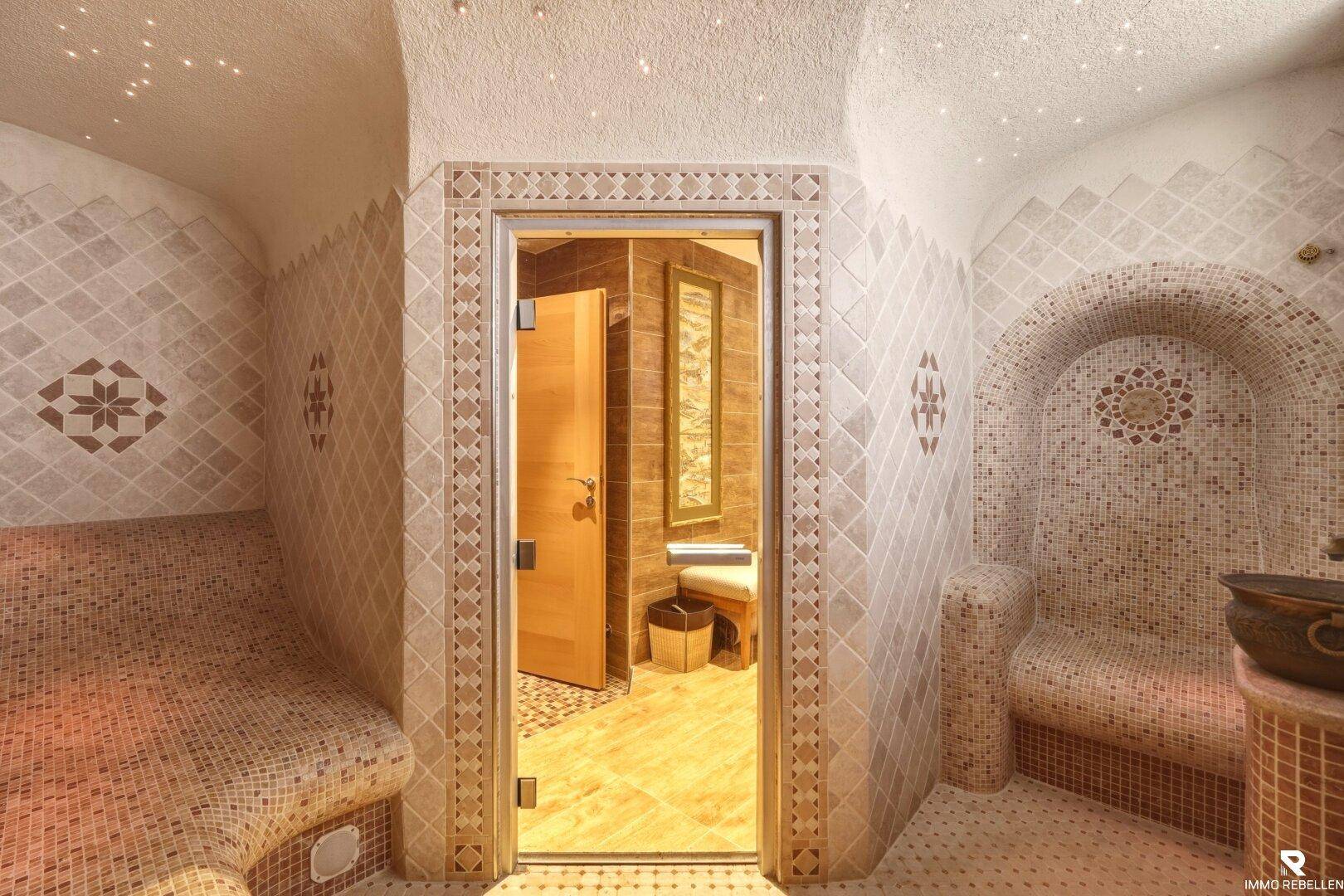 Entspannender Wellnessbereich mit Mosaikfliesen, gewölbter Decke und indirekter Beleuchtung.