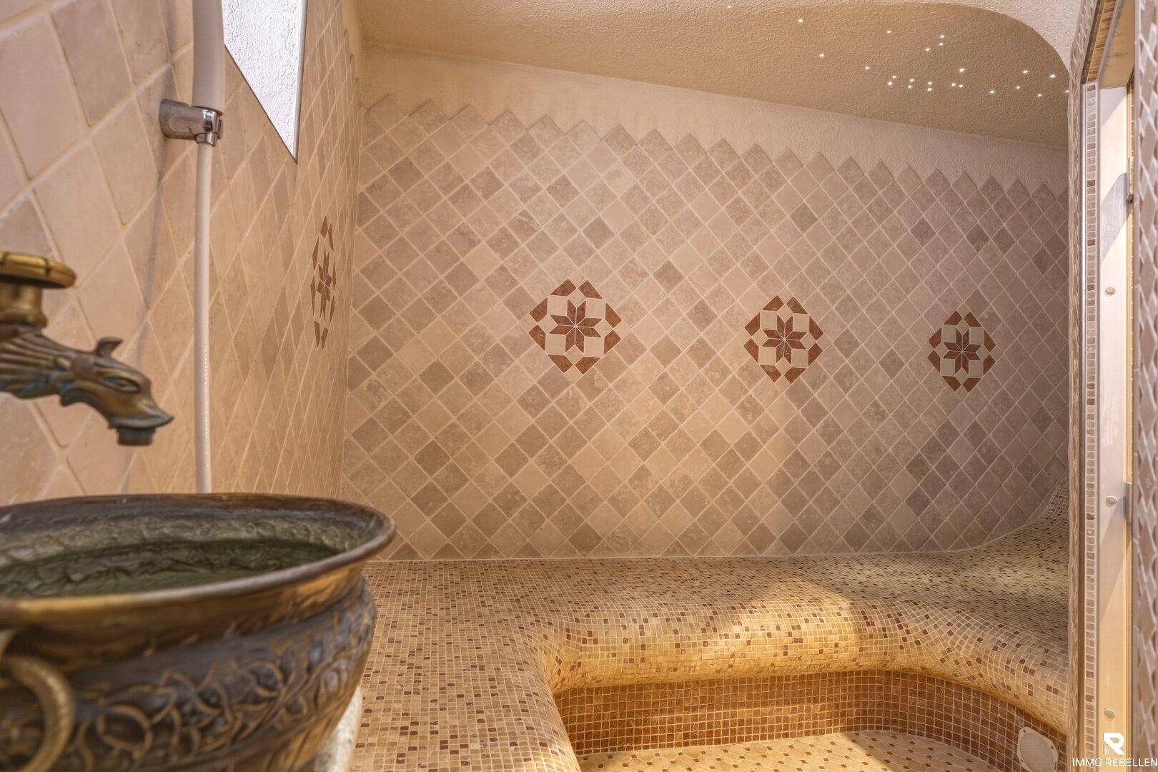 Detailansicht des Wellnessbereichs mit kunstvollen Mosaikfliesen und traditionellem Wasserhahn.