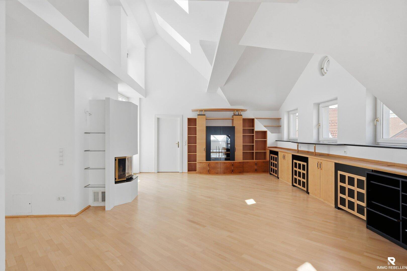 Geräumiger, heller Wohnraum mit Holzboden, Kamin und maßgefertigten Einbauschränken.