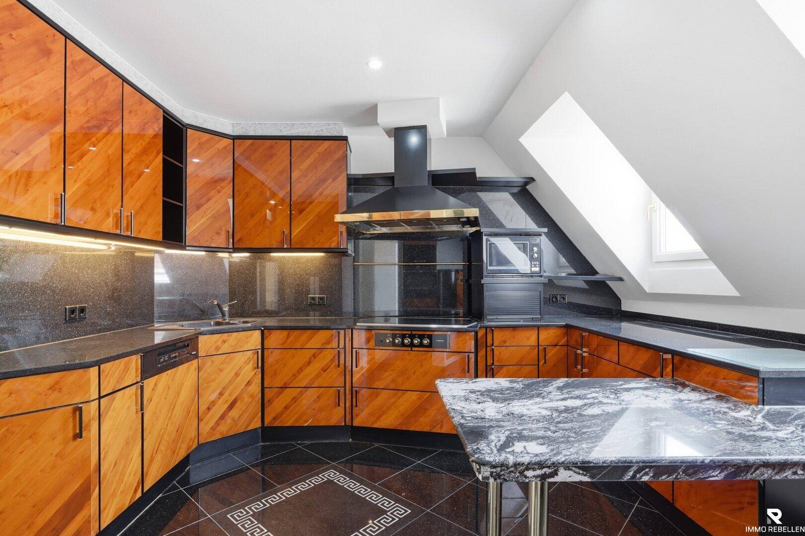 Elegante Küche mit dunklen Granitarbeitsplatten, glänzenden Holzfronten und integrierten Geräten.