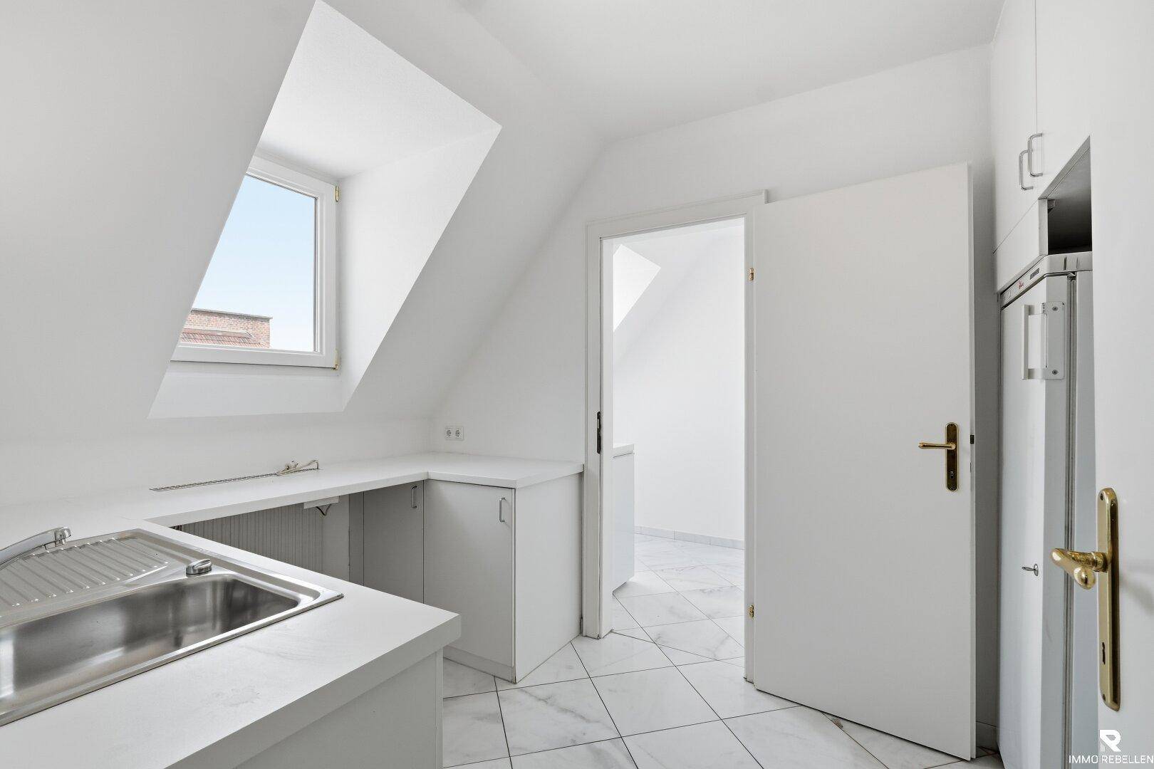 Heller Hauswirtschaftsraum im Dachgeschoss mit Dachfenster, Spülbecken und weißen Fliesenboden.