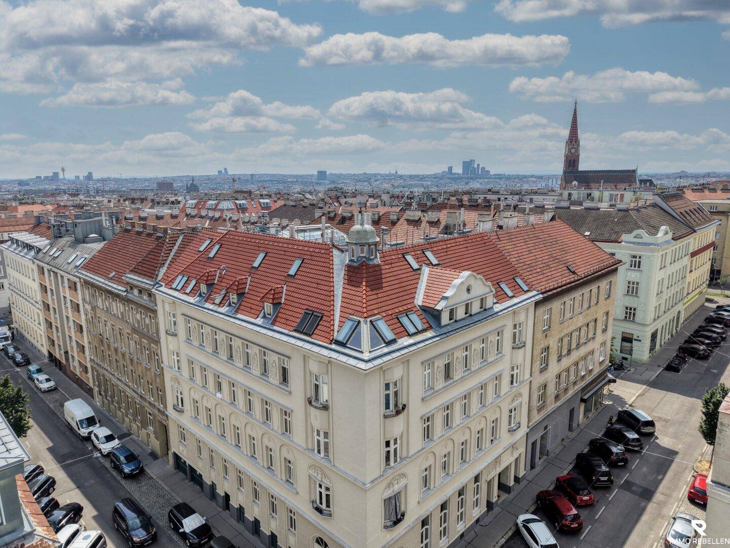 Panoramablick über die Stadt mit historischen Gebäuden, roten Dächern und einer Kirche im Hintergrund.