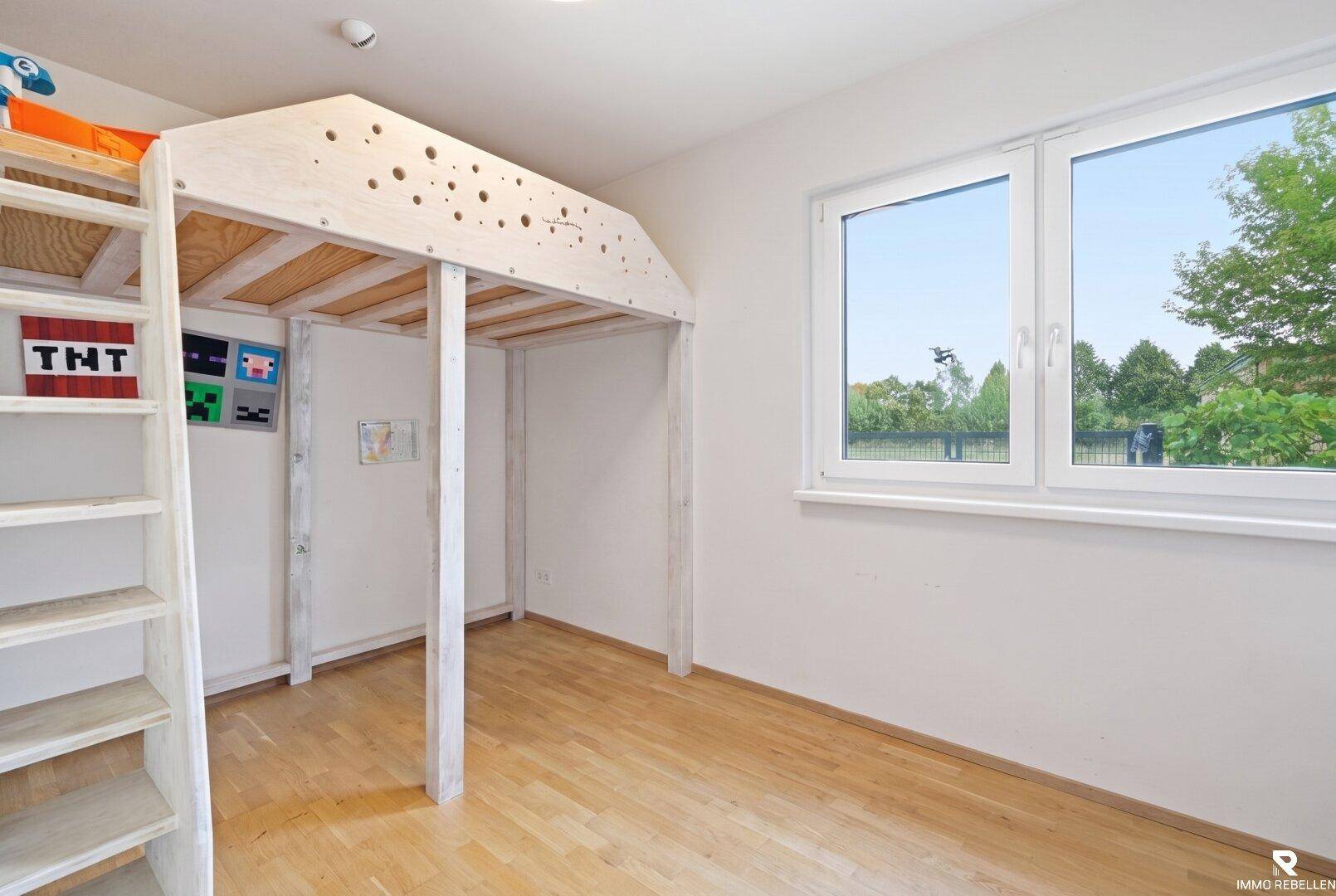 Kinderzimmer mit Hochbett und viel Platz zum Spielen, hell und freundlich.