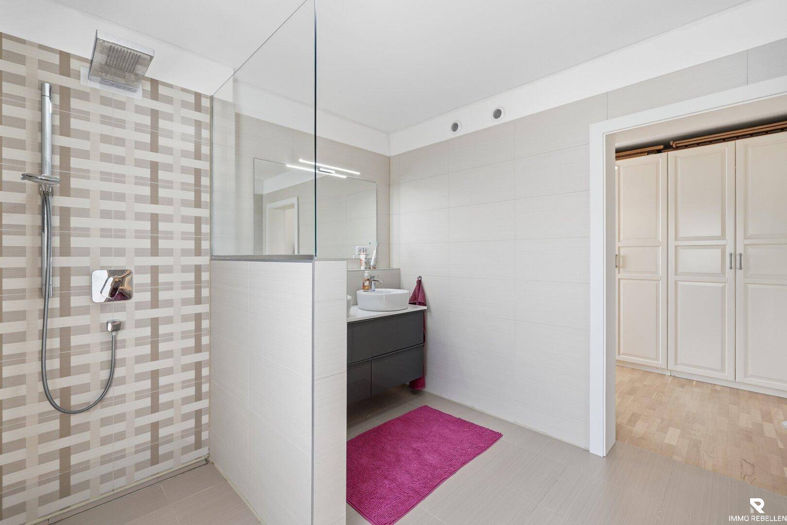 Modernes Badezimmer mit begehbarer Dusche, Waschtisch und hellen Fliesen.