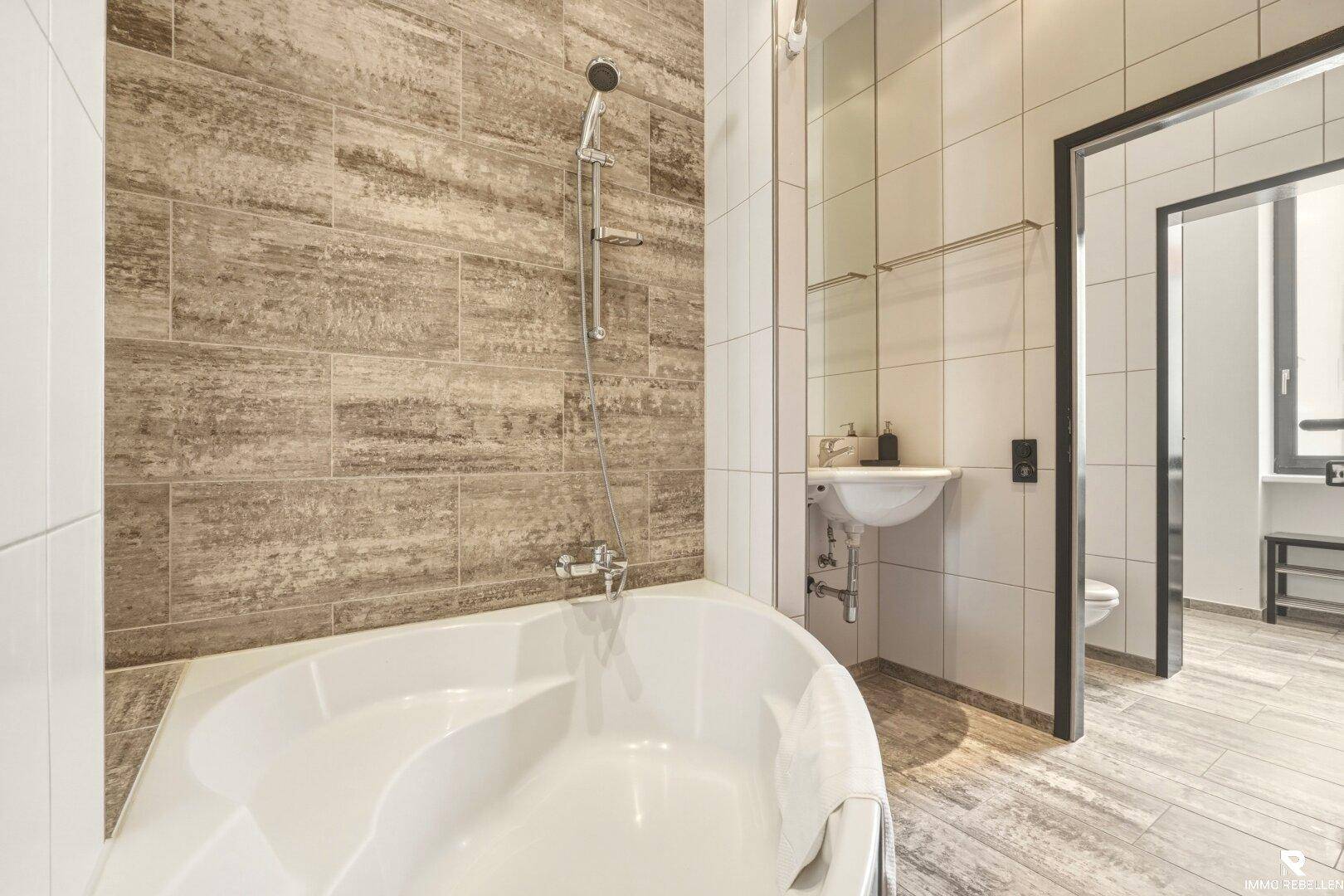 Badezimmer mit Eckbadewanne und modernen Fliesen an den Wänden, funktional und hell.
