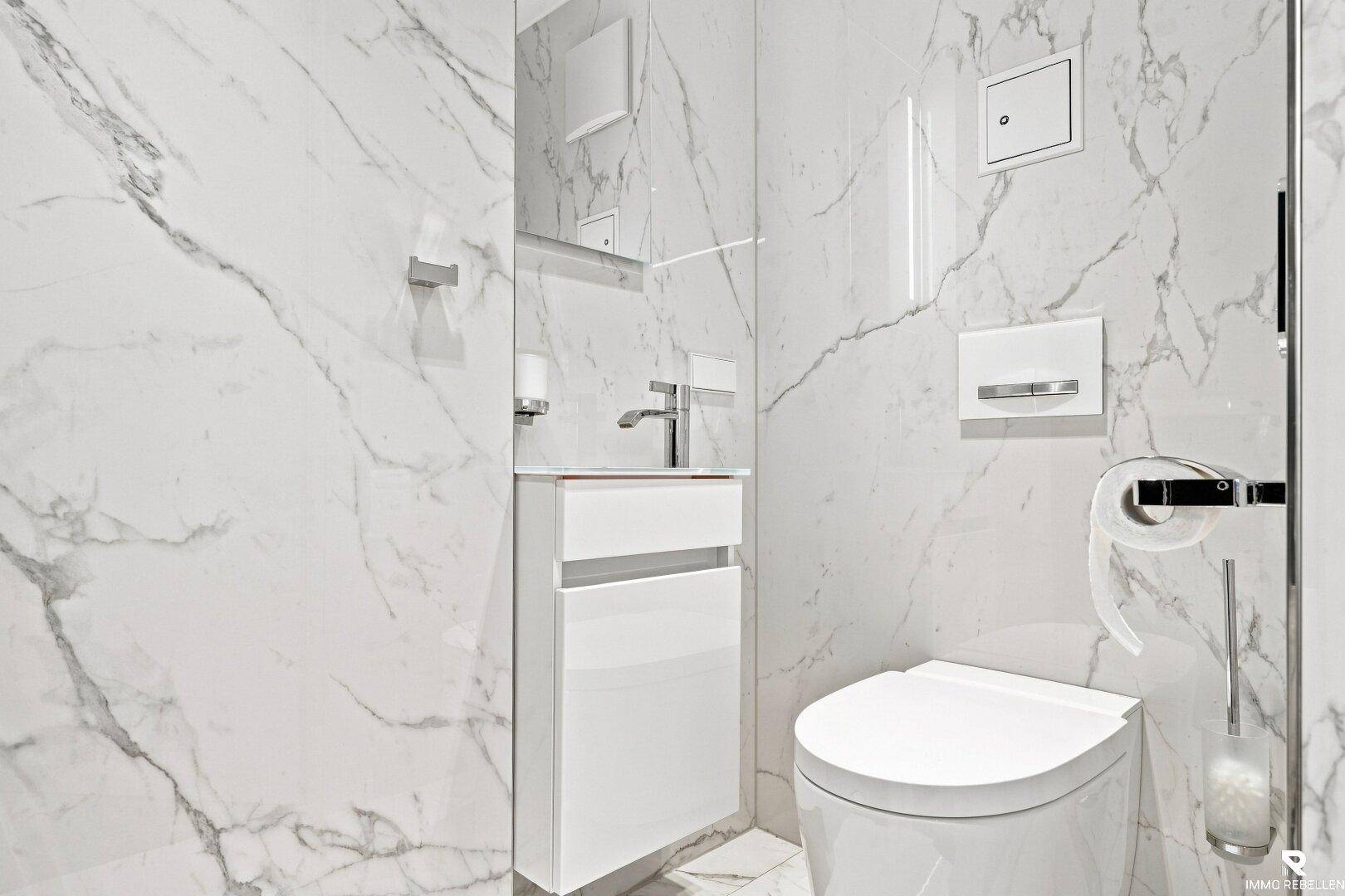 Modernes Gäste-WC mit Marmorfliesen, wandhängendem WC und elegantem Waschtisch.