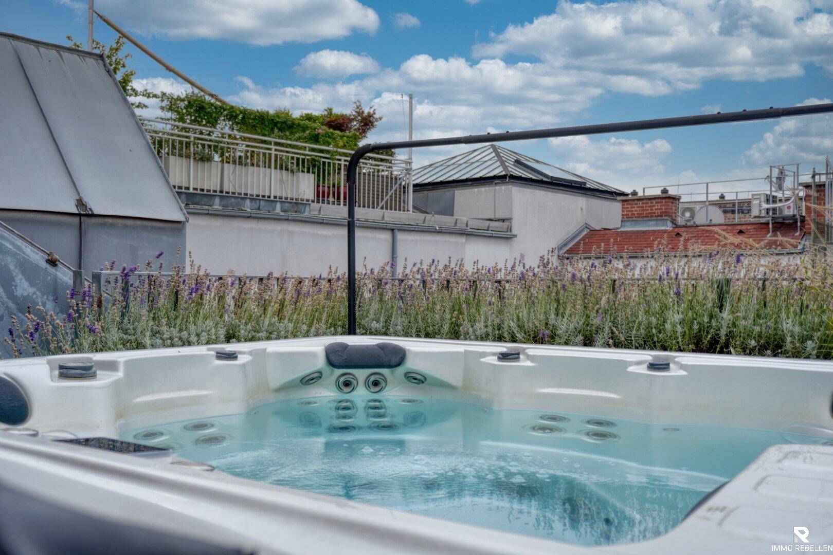 Whirlpool auf der Dachterrasse mit Holzeinfassung und Blick auf die Stadt.