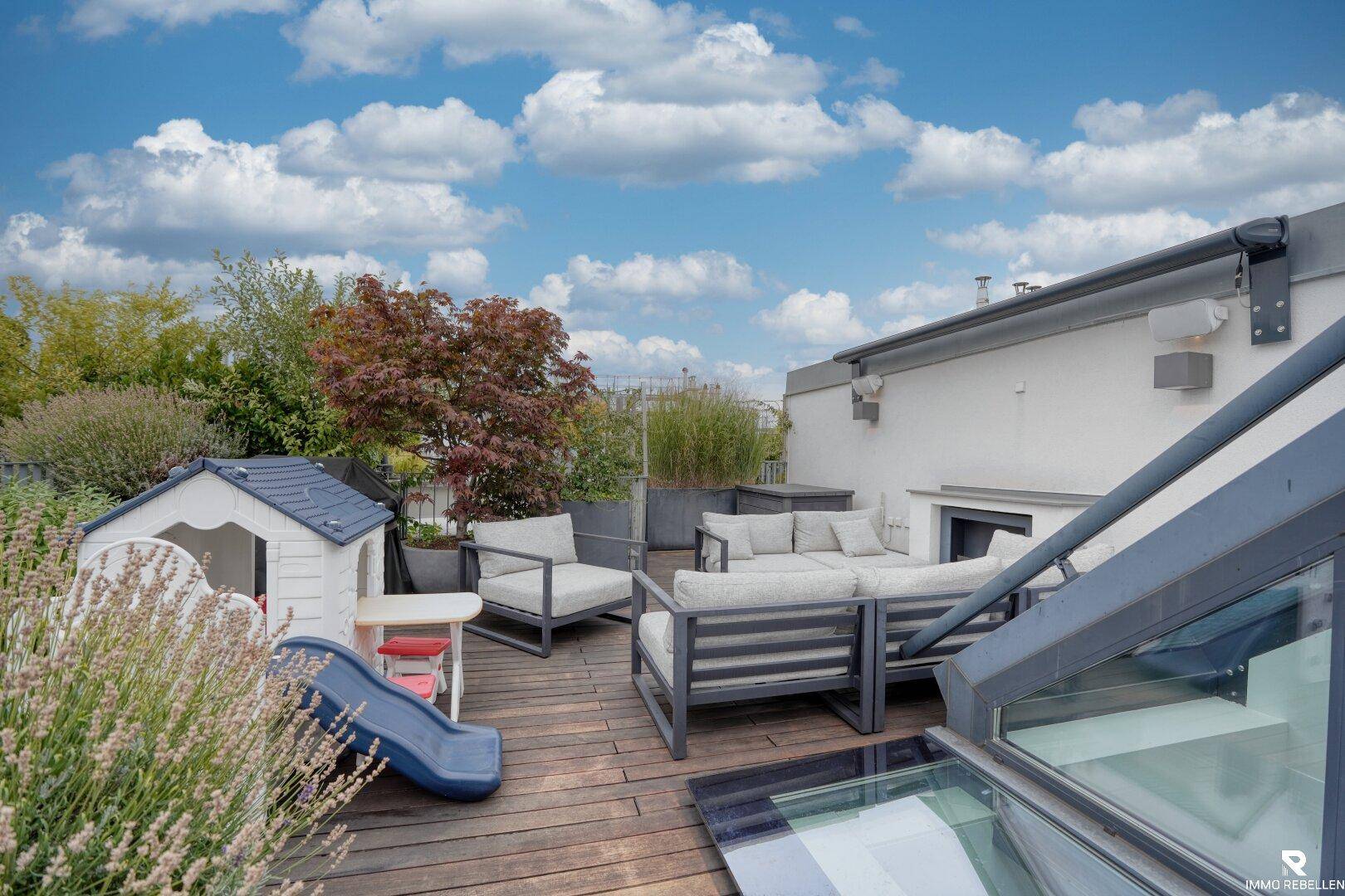 Geräumige Dachterrasse mit Sitzbereich, Kinderspielhaus und üppiger Bepflanzung.