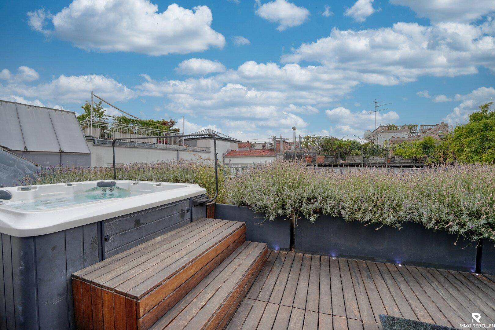 Whirlpool mit Holzstufen auf der Dachterrasse, umgeben von Pflanzen und Beleuchtung.