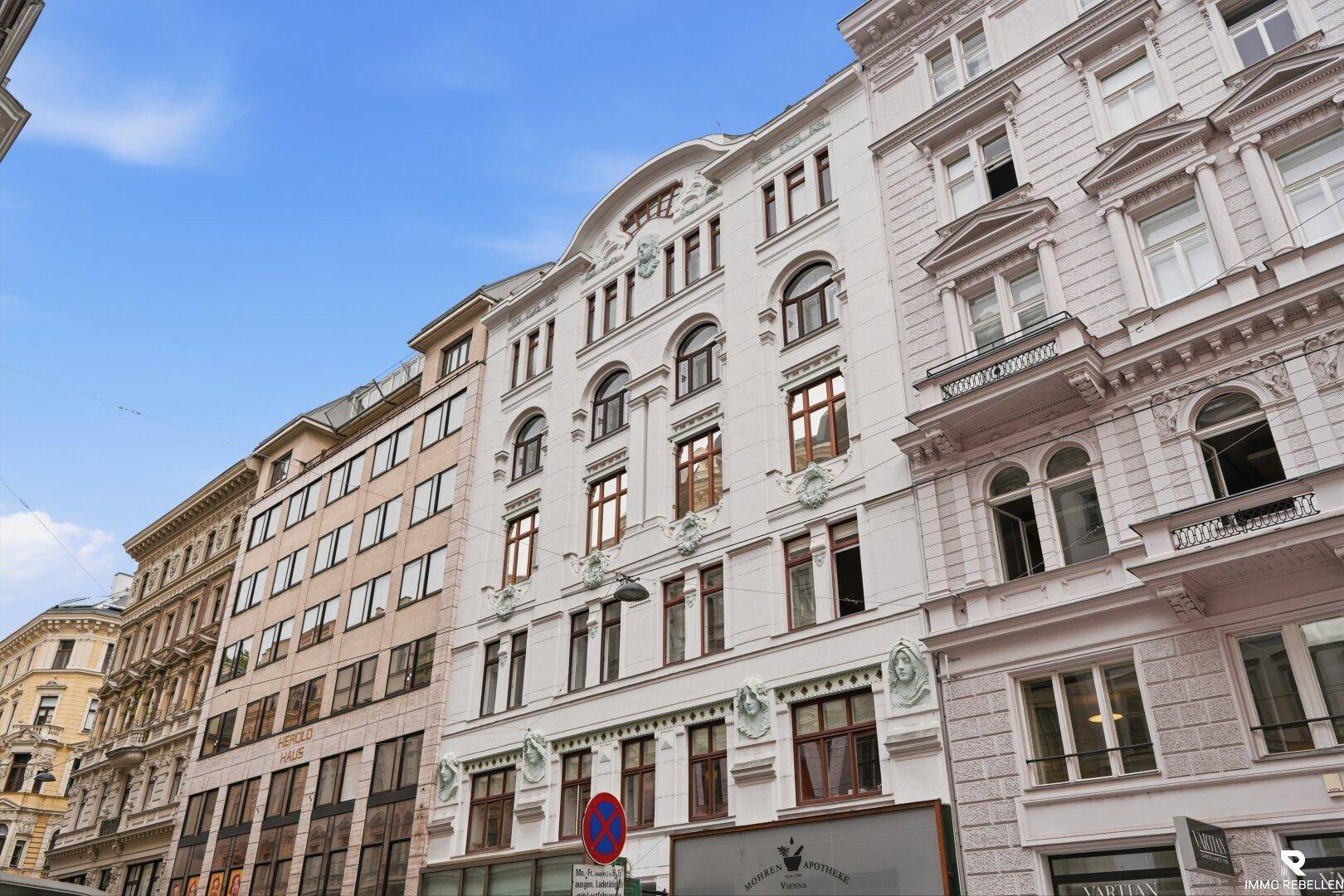 Historische Fassade eines eleganten Stadtgebäudes mit reich verzierten Fenstern und architektonischen Details.