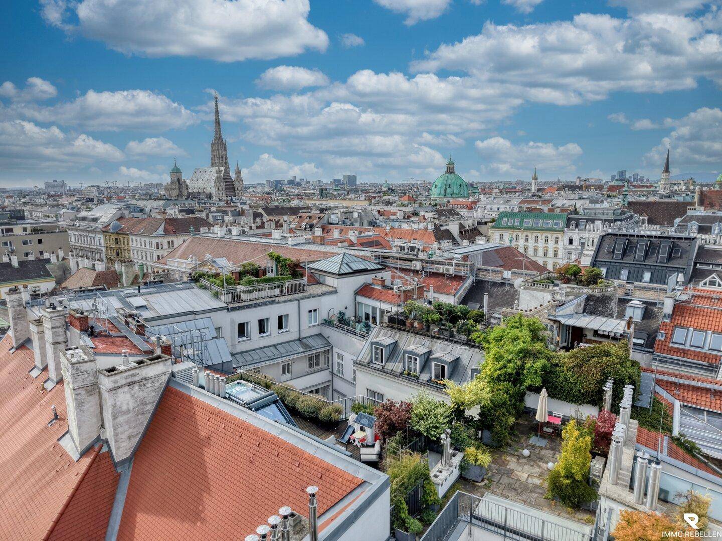Umfassender Blick über die Dächer der Stadt mit zahlreichen Terrassen und dem Stephansdom in der Ferne.