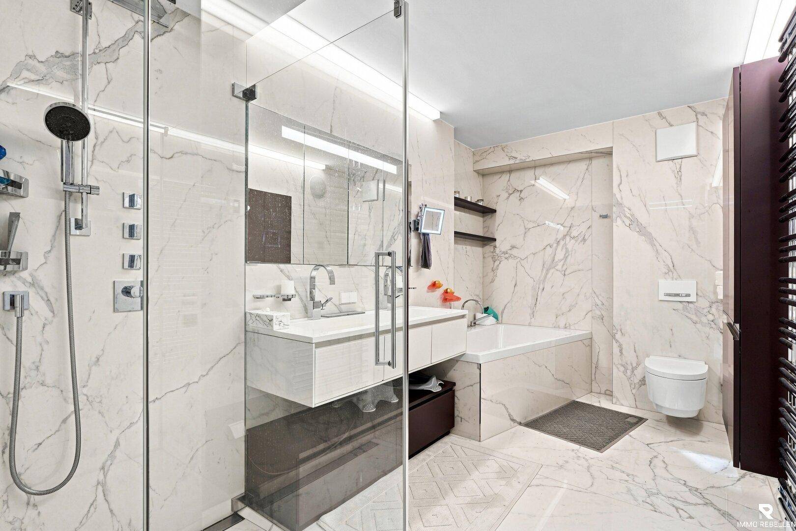 Luxuriöses Badezimmer mit Marmorfliesen, begehbarer Dusche und Badewanne.